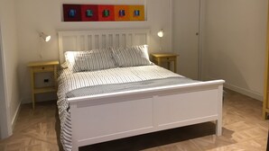 A neatly arranged bedroom with a bed, two bedside tables, a radiator, and a door. - Fafà Apartment in Spaccanapoli (Napoli)