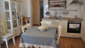 Una cocina con mesa, sillas, un armario con puertas de vidrio, un lavamanos y un horno.