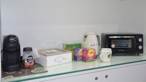 A kitchenette with a coffee maker, a toaster, and various coffee pods.