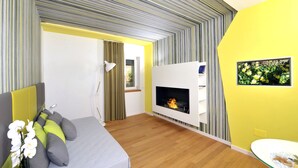 A modern bedroom with a bed, a fireplace, and a yellow accent wall.