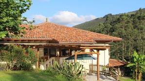 Une maison avec un toit en tuiles, un porche et un petit jardin.