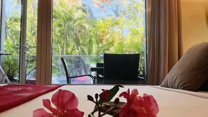 A room with a bed, a window with a view of greenery, and a hanging light fixture. - Hotel les Bougainvilliers (Saint-Paul)