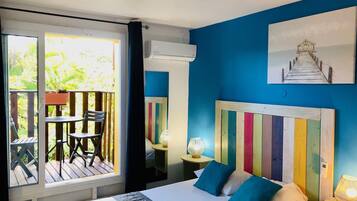 Un dormitorio con una cama grande, vistas a un balcón con mobiliario exterior y un cabecero colorido a rayas.