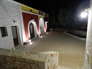 Stunning entrance with arches leading to a covered entrance, surrounded by lush greenery and beautifully lit walkways.