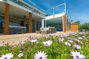 Une maison moderne dotée d’un patio, d’un espace salon extérieur et d’un jardin fleuri.