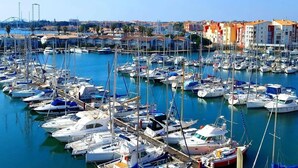 A marina with numerous boats docked, surrounded by buildings and a clear sky.