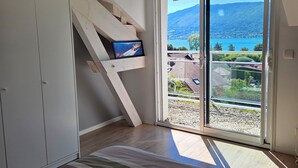 Una habitación con un gran ventanal corredero que da a un balcón con vistas a la montaña.