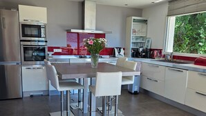 Una cocina moderna con comedor, electrodomésticos de acero inoxidable y un amplio ventanal.