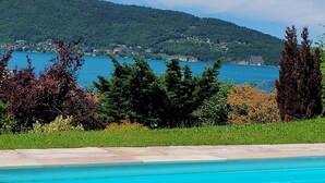Una piscina azul cristalina con vistas a un lago y colinas al fondo.