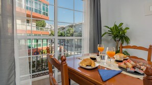 A breakfast table with croissants, juice, and coffee, overlooking a cityscape with buildings and a green area. - SF CARIHUELA LUXURY SUITE (Torremolinos)