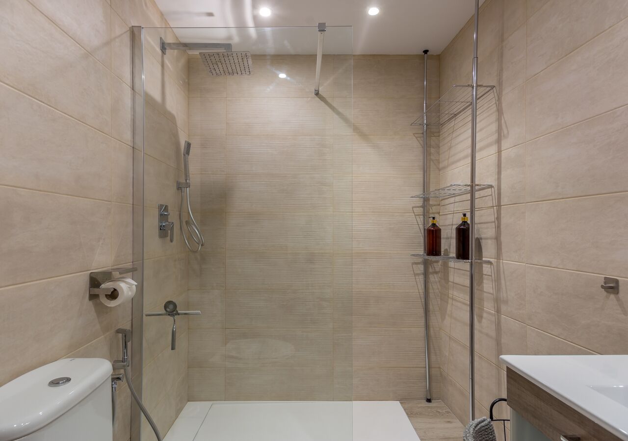 A modern bathroom with a glass-enclosed shower, a toilet, and a sink.