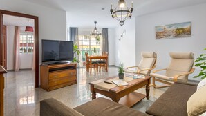 A modern living room with a flat-screen TV, a dining area, and two reclining chairs. - SF CARIHUELA LUXURY SUITE (Torremolinos)