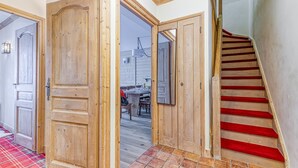 A wooden staircase with red carpet leading to a dining area with a table and chairs. - LES ARCS1950 Very confortable apartment, Southview, snow sure, Indoorpool, Sauna (Bourg-Saint-Maurice)