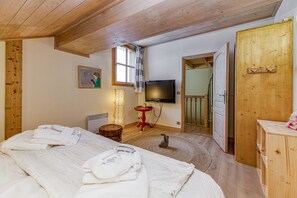 A room with a bed, a TV, a wooden door, and a window.