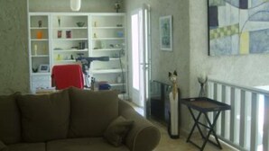 Een woonkamer met een bank, een bijzettafeltje, een boekenkast en een schilderij aan de muur.