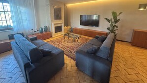 Una sala de estar moderna con un sofá modular, una chimenea, un televisor grande y una planta en maceta.