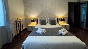 Una habitación de hotel con una cama grande, dos mesitas de noche con lámparas, un armario y un espejo.