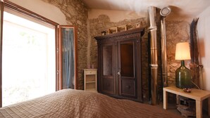 Ein Schlafzimmer mit einem Bett, einem Holzschrank, einer Lampe und einer Steinwand.