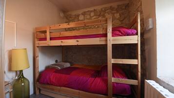 A bunk bed with a stone wall backdrop, a lamp, and a radiator.