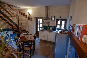 Cozy kitchen with stove, dining area, and staircase to upper level.