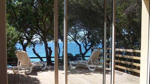 A room with a large window overlooking a wooden deck with two white lounge chairs. - House / Villa - Rayol-Canadel-sur-Mer (Rayol-Canadel-Sur-Mer)