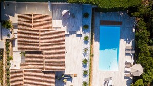 Ett flygbildsfoto av en fastighet med en swimmingpool, utomhusmöbler och en uteplats med kakelplattor.