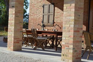Eine Terrasse im Freien mit Ziegelwand, Holztisch und Stühlen.
