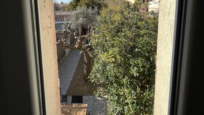 A view from a window overlooking a courtyard with a tiled roof, a tree, and a building with a tower.