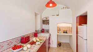 Uma cozinha compacta com uma luminária pendente vermelha, uma geladeira branca e um painel de azulejos.