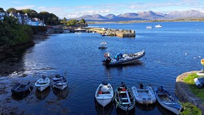 A harbor with boats docked, a pier, and a mountainous backdrop. - Luxury Connemara Cottage With Panoramic Views Of The Sea And Mountains  (Rosmuc)