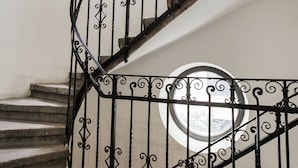 A spiral staircase with ornate black metal railings and a circular window at the top.