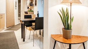 A modern, well-lit room with a dining area, a potted plant, and a lamp.