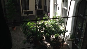 A courtyard with arched windows, potted plants, and a brick floor.