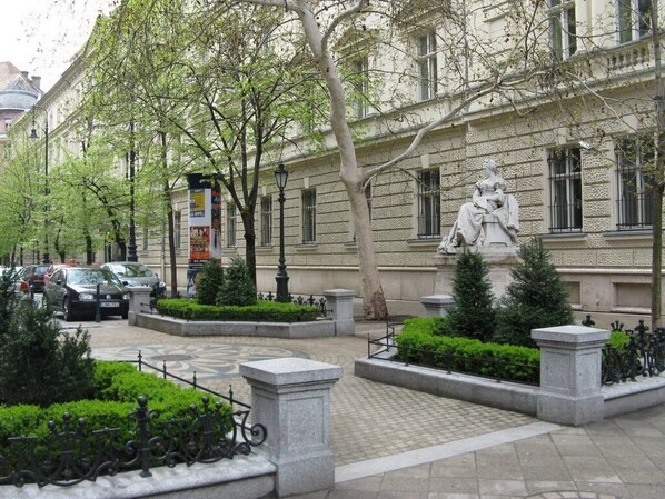 A courtyard with a statue, a fountain, and a building with classical architecture.