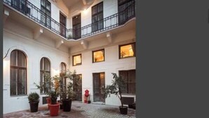 A courtyard with a tiled floor, potted plants, and a red fire hydrant.