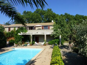 Un bâtiment à deux étages doté d’une piscine, d’un espace extérieur aménagé et d’une végétation luxuriante.
