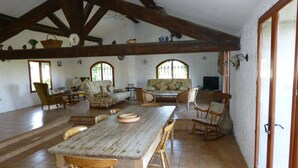 A spacious room with a wooden table, chairs, a sofa, and a television.