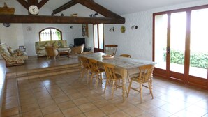 A spacious living area with a dining table, chairs, a sofa, and a television.