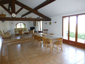 A spacious living area with a dining table, chairs, a sofa, and a television.