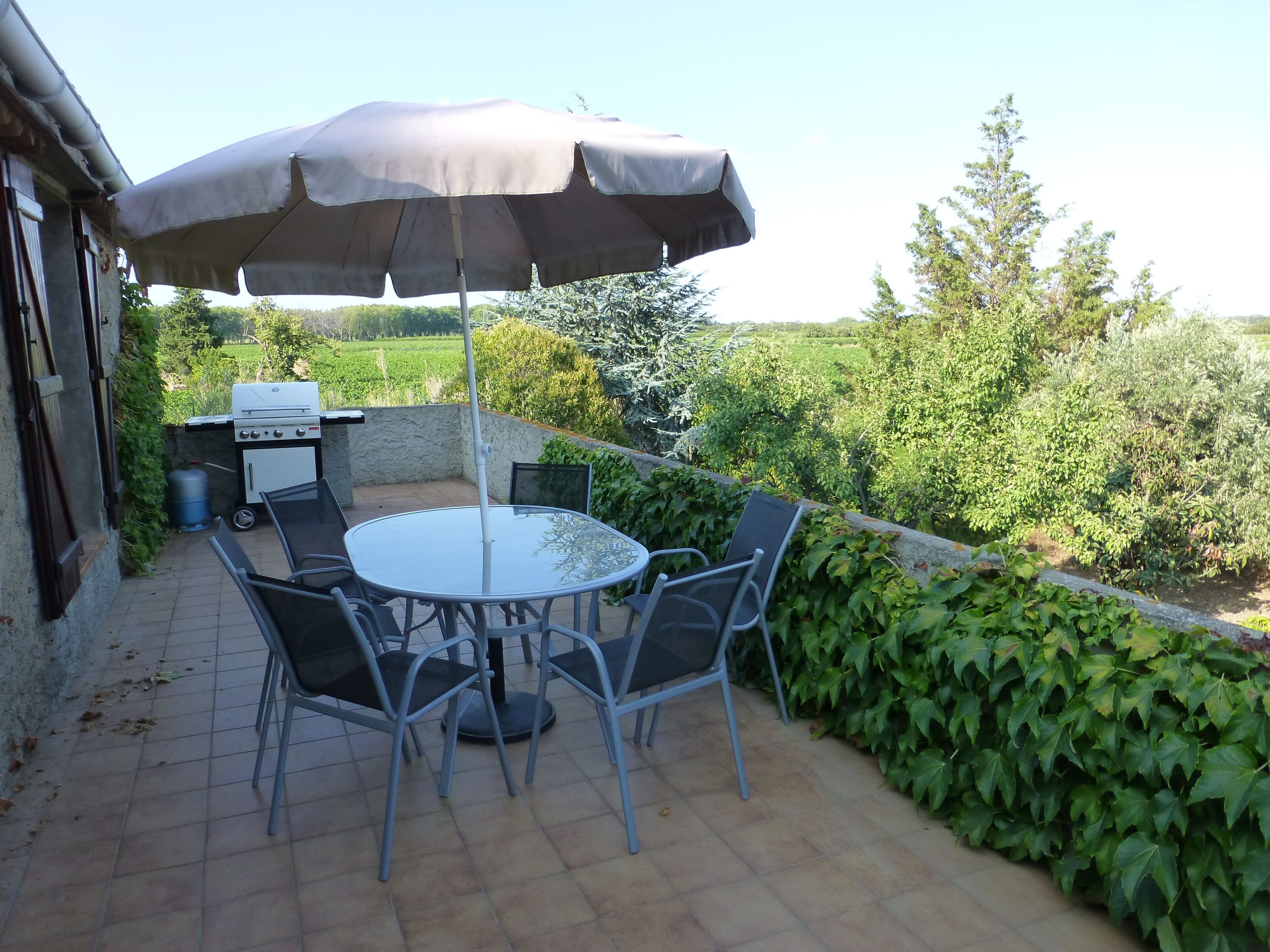 An outdoor patio with a round table, chairs, and a large umbrella.