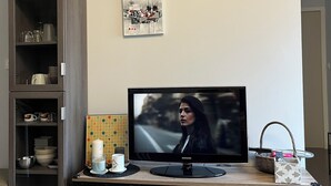 Un soggiorno moderno con televisore a schermo piatto, mobile TV in legno, condizionatore d'aria fissato al muro e decorazioni murali.