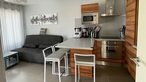 Una cucina compatta con forno a microonde, macchina del caffè e forno. È presente un'area pranzo con tavolo e sedie.