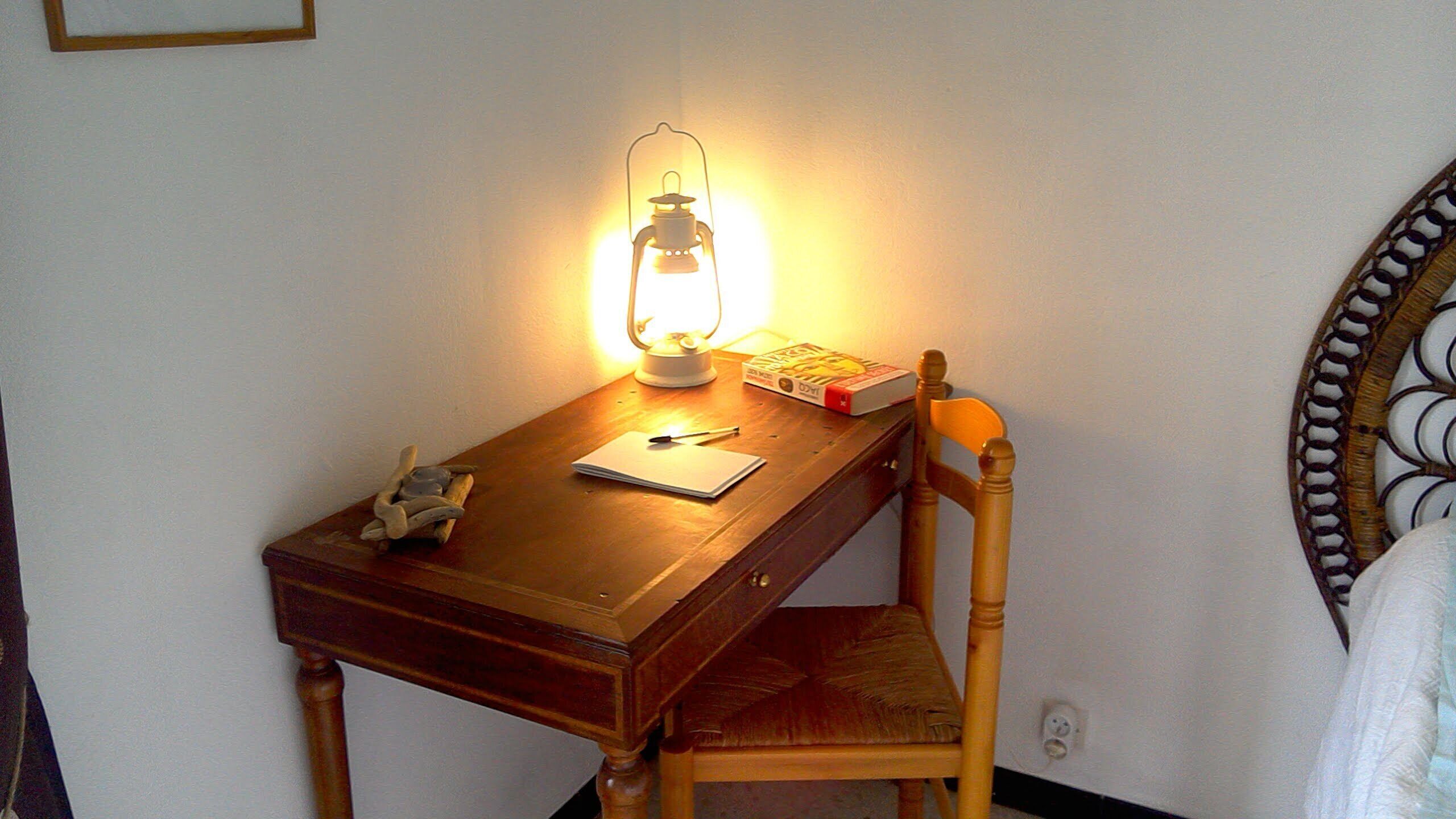 Una scrivania in legno con una lampada, un libro e una penna.