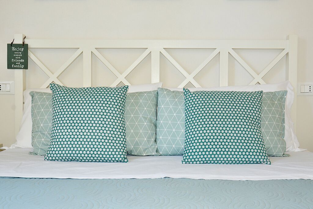 A bed with a white headboard and two pillows with a geometric pattern.