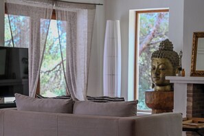 Uma sala de estar com sofá, uma estátua de Buda, lareira e televisão.