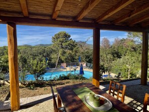 Une pergola en bois surplombant une piscine, avec vue sur les arbres et les collines.