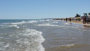 Een strand met mensen, parasols en een heldere lucht.