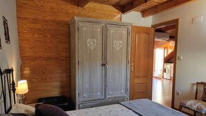 A bedroom with a bed, a wardrobe, and a wooden ceiling. - Maribel Tourist Apartment for 5 people (Biescas)