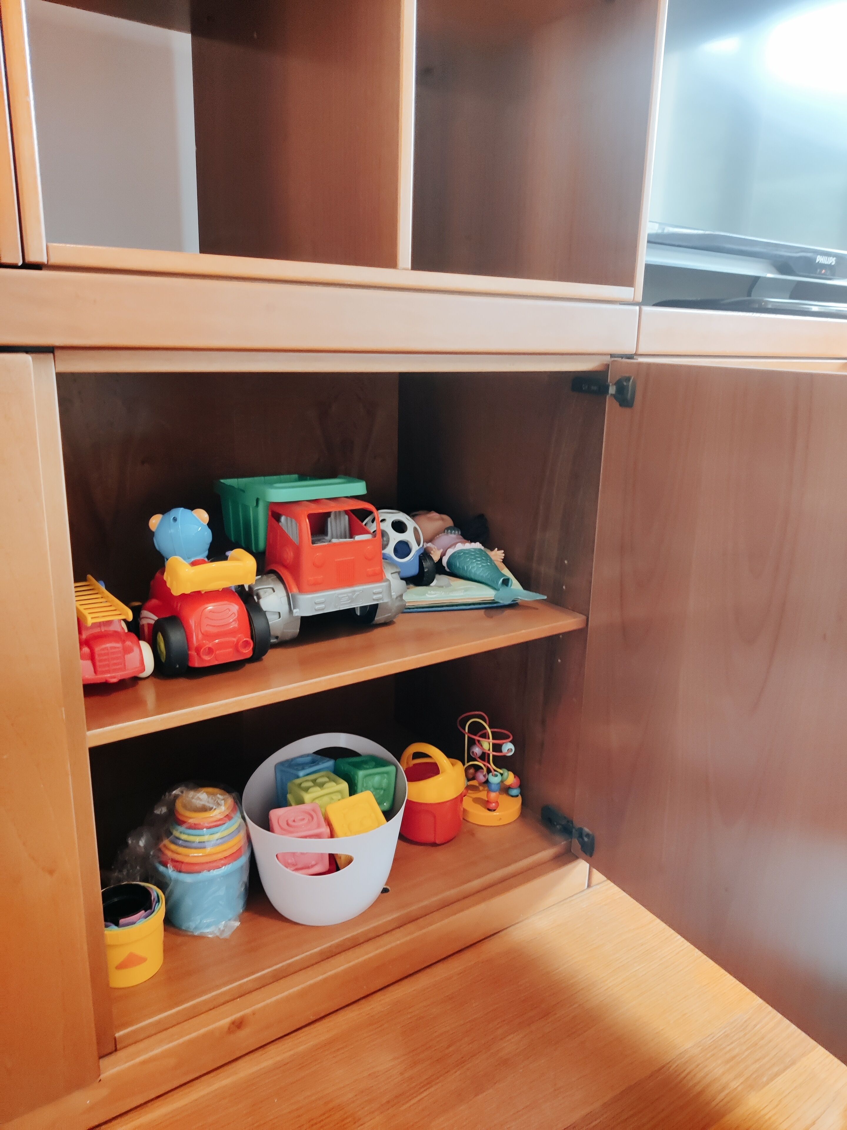 Un mueble de madera con estantes que contiene juguetes y cajas de almacenamiento.