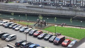 A parking lot with cars and a river in the background. - FLAT in the CENTER OF ONDARROA, fishing village, with WIFI 600MB, without slopes. (ONDARROA)